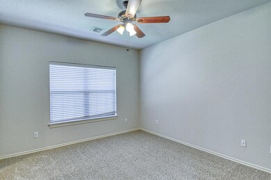Carpeted spare room with visible vents, ceiling fa