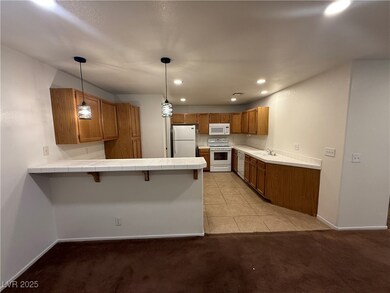 Kitchen with white appliances, a peninsula, brown