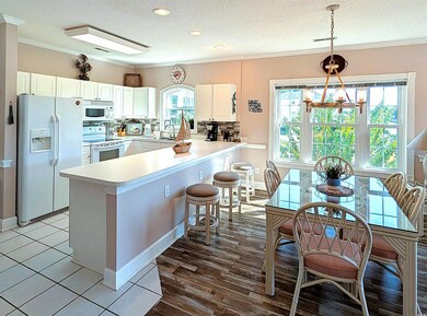 Kitchen with decorative backsplash, white appliances, a textured ceiling, ornamental molding, and a peninsula