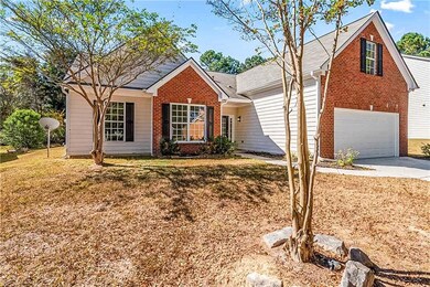 View of front of house featuring a front lawn, brick siding, driveway, and an attached garage