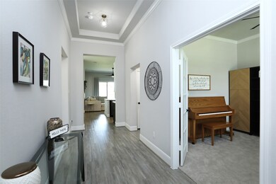 Step into unparalleled luxury as 8' front doors open into a stunning interior. Begin your journey with a gorgeous open floor plan that flows seamlessly accented by a tray ceiling, complemented by vinyl plank flooring and neutral paint that create a sense of warmth and sophistication. The inviting open floor plan welcomes abundant natural light, creating a bright and airy atmosphere throughout.