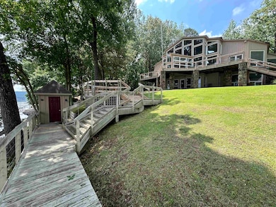 Back of property with a yard, stone siding, and a deck