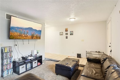 Tiled living room featuring visible vents and a te