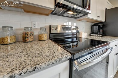 Kitchen with white cabinetry, tasteful backsplash,