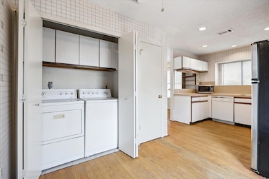 Laundry area featuring light wood finished floors, washing machine and clothes dryer, recessed lighting, and a textured ceiling