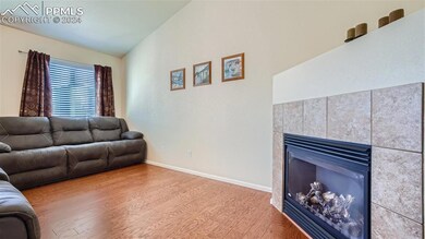 Living room with a tiled fireplace, light wood flo