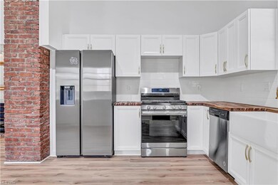 Kitchen featuring brick wall, stainless steel appl