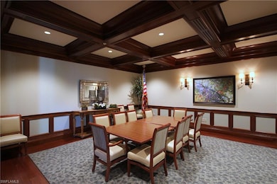 Dining space with wainscoting, a decorative wall, dark wood-style flooring, and coffered ceiling