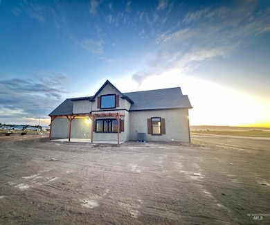 View of front of house with stucco siding, roof with shingles, and a patio