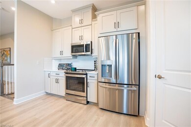 Kitchen with appliances with stainless steel finishes, white cabinetry, light wood-style floors, and tasteful backsplash