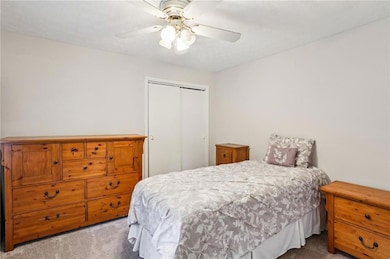 Bedroom featuring light colored carpet, a closet, and ceiling fan.