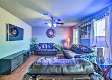 Living area featuring a textured ceiling, wood finished floors, and ceiling fan