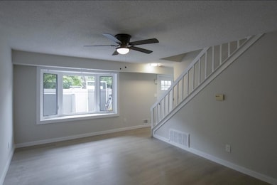 Unfurnished living room with wood finished floors, a ceiling fan, stairway, and a textured ceiling