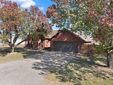View of front of home featuring gravel driveway, brick siding, and a garage