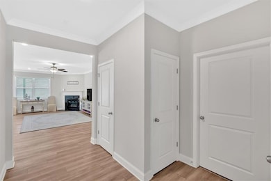 Hallway with crown molding, light wood-type floori