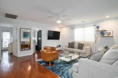 Living room featuring visible vents, baseboards, a ceiling fan, and dark wood-style floors