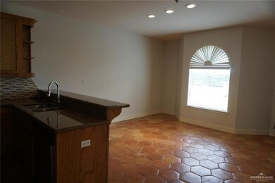 Kitchen with tasteful backsplash, dark stone counters, light tile floors, and sink