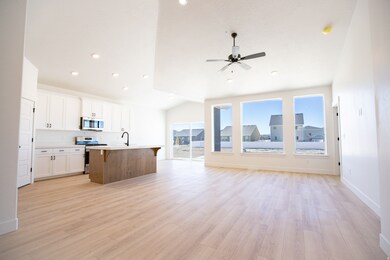 Spacious great room/family room with vaulted ceiling, ceiling fan and picture windows.