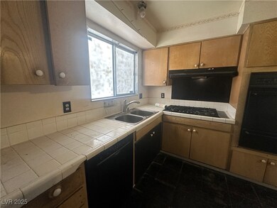 Kitchen featuring a sink, tile counters, dishwashe