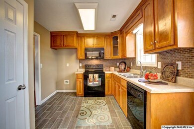 Kitchen features black appliances, tiled back splash and pantry