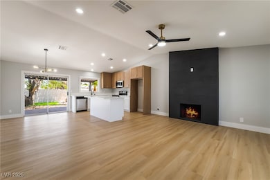 Unfurnished living room with a ceiling fan, a fire