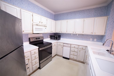 This kitchen features white cabinetry with ample s