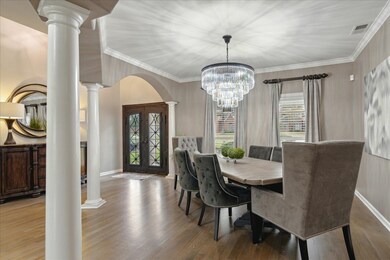 Dining space with decorative columns, hardwood / wood-style floors, a notable chandelier, and ornamental molding