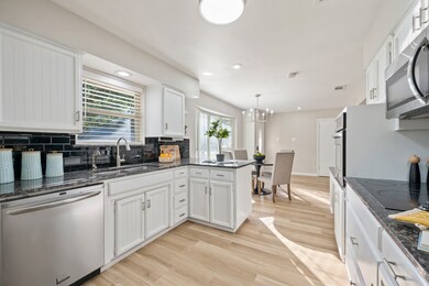Kitchen featuring stainless steel appliances, white cabinets, dark stone counters, and recessed lighting