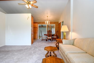 Living room with a chandelier, light colored carpet, and a ceiling fan