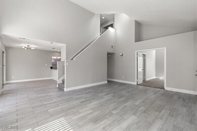 Unfurnished living room featuring high vaulted ceiling, light wood-type flooring, and stairway