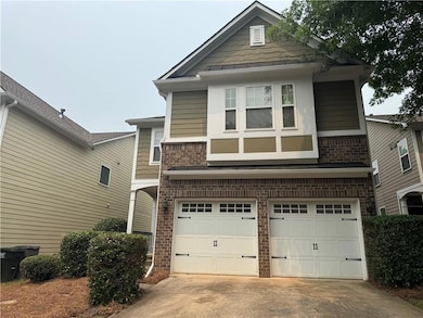 View of front facade with a garage, concrete driveway, brick siding, and a standing seam roof