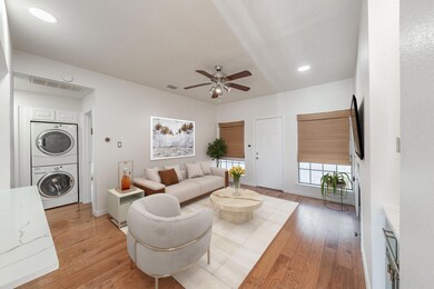 Living room featuring ceiling fan, stacked washer 