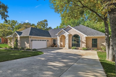 View of front facade featuring a shingled roof, brick siding, and driveway