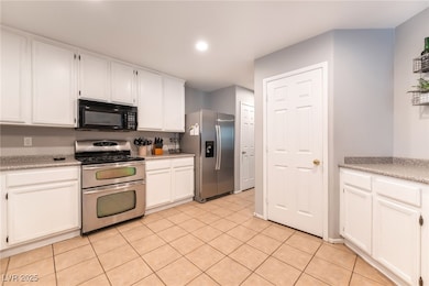 Kitchen with appliances with stainless steel finishes, white cabinetry, light tile patterned flooring, and recessed lighting