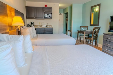 Bedroom with wet bar, baseboards, and wood finished floors