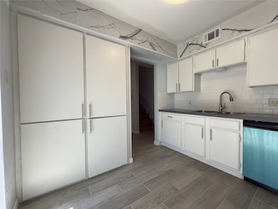 A view of the kitchen with the cabinets provided to the hallway