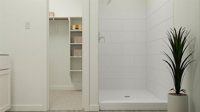 Bathroom with a shower stall and a spacious closet