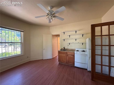 Kitchen with white appliances, dark wood-style floors, open shelves, a ceiling fan, and a textured ceiling
