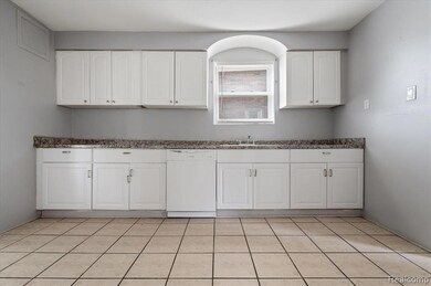 Kitchen featuring white dishwasher, white cabinets, and light tile patterned flooring