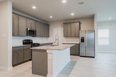 Kitchen featuring visible vents, a sink, light wo