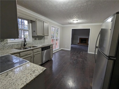 Kitchen with dark hardwood / wood-style floors, sink, appliances with stainless steel finishes, and backsplash