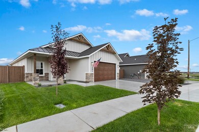 View of front of house with board and batten siding, driveway, a standing seam roof, a garage, and stone siding
