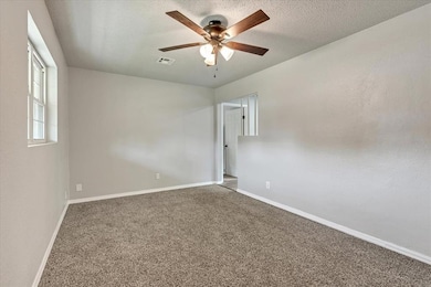 Empty room with ceiling fan, baseboards, carpet, and a textured ceiling