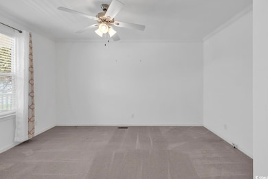 Unfurnished room with carpet flooring, a ceiling fan, and crown molding