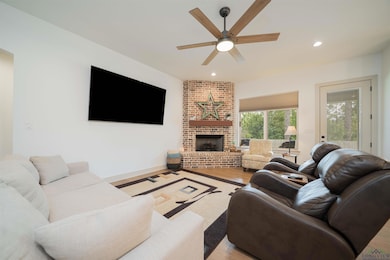 Living room with recessed lighting, a brick fireplace, ceiling fan, and wood finished floors