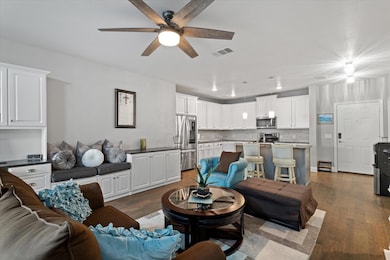 Living area  featuring a ceiling fan, dark wood fi