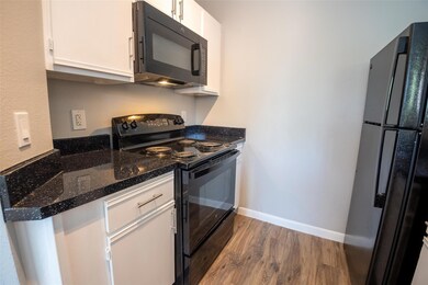 Kitchen with black appliances, wood finished floo