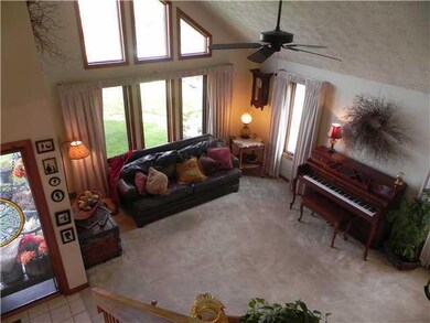 Living Room two story living room with trapezoid transom windows and woodburning fireplace