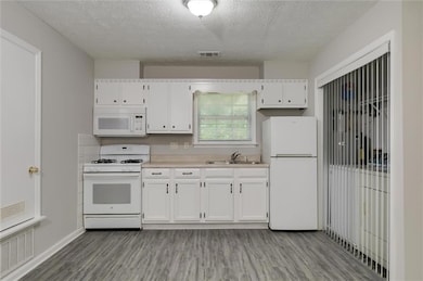 Kitchen with white appliances, light countertops, a sink and laundry area