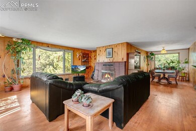 Living room featuring large front window, paneled walls, a wood burning fireplace and original wood flooring
